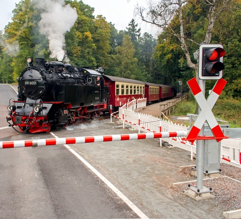 Dampflok fährt über Bahnübergang